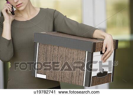 Stock Image - Businesswoman Using Mobile Phone with Moving Box. Fotosearch