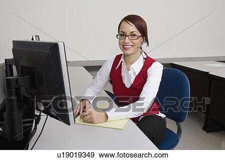 Stock Photo - Cheerful Businesswoman Sitting at Desk. Fotosearch