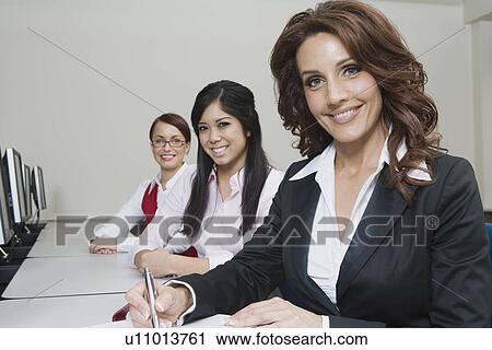 Stock Image - Cheerful Multi Racial Businesswomen Sitting at Desk. Fotosearch