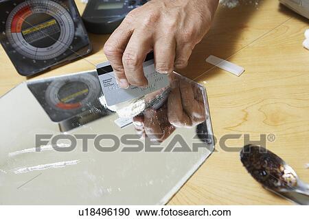 Stock Image - Close-up of man's hand and cocaine. Fotosearch