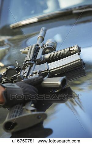 Stock Image - Close-up of police weapon on car bonnet. Fotosearch