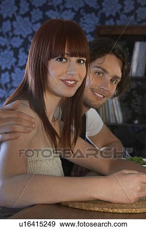 Stock Photo - Couple embracing sitting at table portrait. Fotosearch