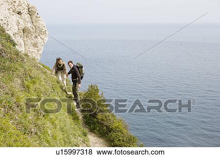 Stock Photo - Couple Hiking on a Path Above the Water. Fotosearch