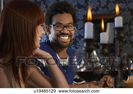 Stock Photo - Couple laughing sitting at dining table close up. Fotosearch