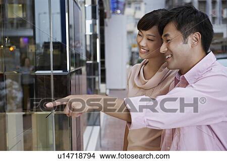 Couple looking through shop window at display View Large Photo Image Picture - Couple looking through shop window at display. Fotosearch