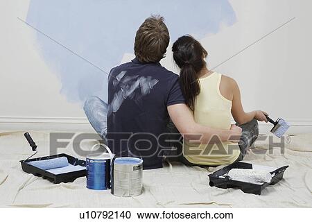 Couple looking up at half-painted wall View Large Photo Image Stock Image - Couple looking up at half-painted wall. Fotosearch
