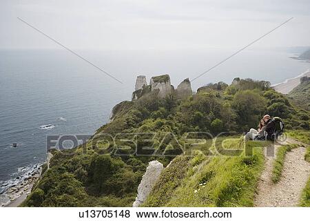 Stock Photo - Couple Sitting on an Outlook Above the Water. Fotosearch