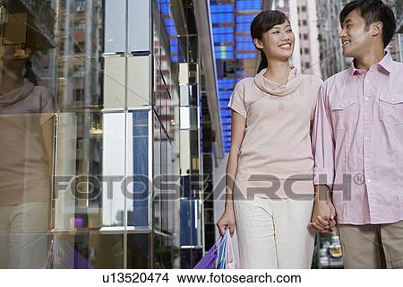 Couple walking past store looking in eyes and smiling View Large Photo Image Picture - Couple walking past store looking in eyes and smiling. Fotosearch