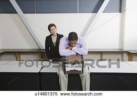 Stock Photography - Depressed Man Sitting on Desk with Moving Box. Fotosearch