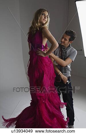 Stock Photo - Designer Adjusting Dress Back on Fashion Model. Fotosearch