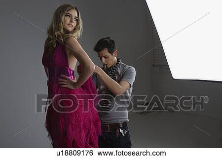 Stock Photograph - Designer Adjusting Dress Back on Fashion Model. Fotosearch