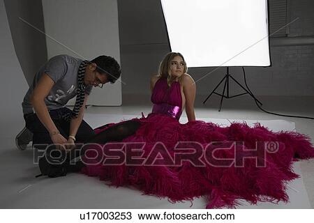 Stock Image - Designer Adjusting Shoe on Fashion Model. Fotosearch
