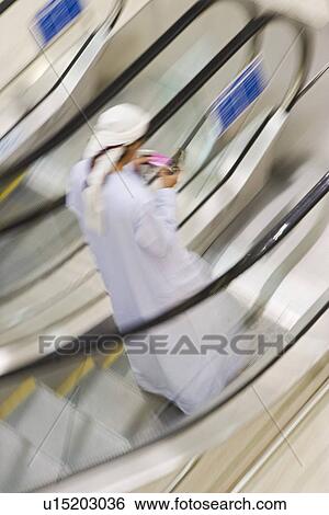 Stock Photograph - Dubai UAE A man traditionally dressed in a dishdash and gutra white robe and headdress.. Fotosearch