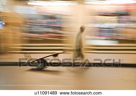 Dubai UAE A man wheels an empty cart through the streets of Deira just after dark. View Large Photo Image Stock Photo - Dubai UAE A man wheels an empty cart through the streets of Deira just after dark.. Fotosearch