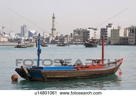 Stock Image - Dubai UAE empty abra anchored on Dubai Creek with minaret of Grand Mosque in distance. Fotosearch