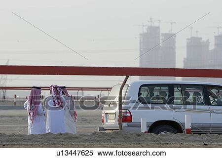 Stock Photography - Dubai UAE group of Muslim men wearing traditional dishdash and gutras. Fotosearch