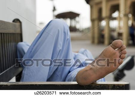 Stock Image - Dubai UAE man taking rest on park bench along boardwalk in Bur Dubai. Fotosearch