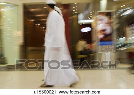 Stock Image - Dubai UAE Two men traditionally dressed in dishdashs and gutras white robes and headdresses.. Fotosearch