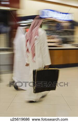 Stock Photograph - Dubai UAE Two men traditionally dressed in dishdashs and gutras white robes and headdresses.. Fotosearch