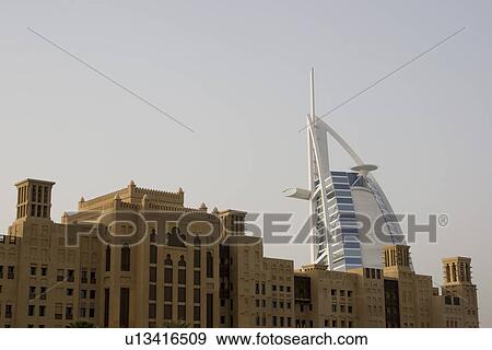 Stock Photo - Dubai UAE world famous Burj Al Arab Hotel seen beyond old windtowers. Fotosearch