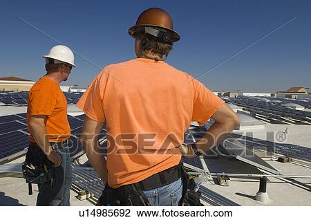 Stock Image - Electrical Engineers Working at Solar Power Plant. Fotosearch