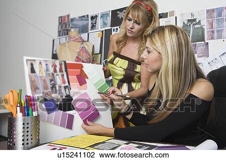 Stock Image - Female fashion designers working at desk. Fotosearch