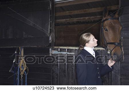 Stock Image - Female horseback rider with horse in stable. Fotosearch