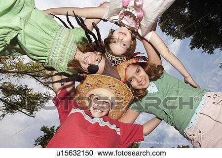 Stock Image - Four children (7-12) in huddle. Fotosearch