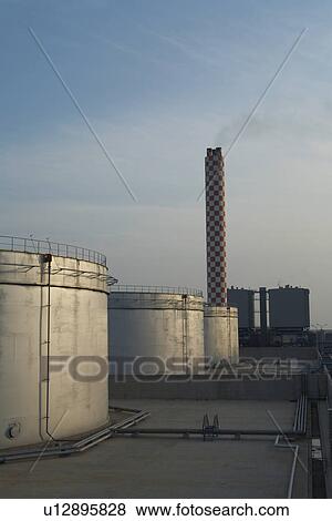 Stock Photo - Fuel oil storage tanks with power station and smokestack in background. Fotosearch