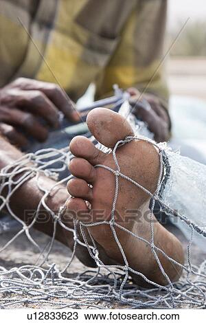 Fujairah UAE A local fisherman fixes holes and tangles in his net in Fujairah. View Large Photo Image Stock Image - Fujairah UAE A local fisherman fixes holes and tangles in his net in Fujairah.. Fotosearch