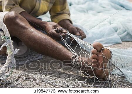 Fujairah UAE A local fisherman fixes holes and tangles in his net in Fujairah. View Large Photo Image Stock Image - Fujairah UAE A local fisherman fixes holes and tangles in his net in Fujairah.. Fotosearch