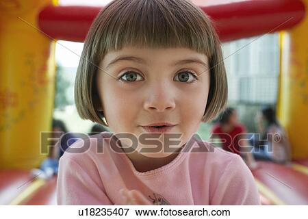 Stock Photo - Girl (5-6) in bouncy castle portrait close up. Fotosearch