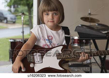 Stock Image - Girl (5-6) sitting in garage with guitar. Fotosearch