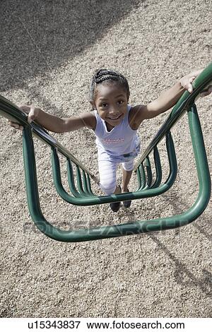 Stock Photo - Girl (7-9) climbing jungle gym. Fotosearch