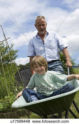 Grandfather pushing boy in wheel barrow View Large Photo Image Stock Photo - Grandfather pushing boy in wheel barrow. Fotosearch