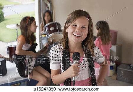 Group of girls (7-9) with instruments in garage focus on singer in foreground View Large Photo Image Stock Image - Group of girls (7-9) with instruments in garage focus on singer in foreground. Fotosearch