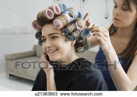 Stock Image - Hairstylist Rolling Hair of Model. Fotosearch