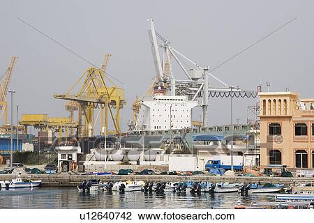 Stock Image - Khor Fakkan UAE Large cargo ships docked to load and unload goods at Khor Fakkport. Fotosearch