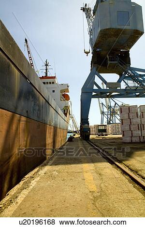 Stock Photo - Limassol Cyprus. Crane loading a freighter with cargo on quayside. Fotosearch
