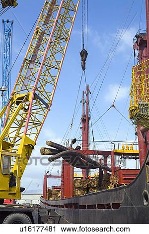 Stock Image - Limassol Cyprus. Dockside crane unloading steel rods from a freighter. Fotosearch