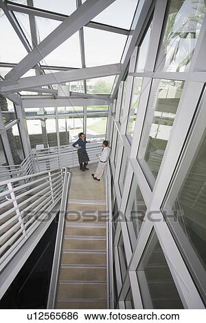 Stock Photograph - male and Female Business People Talking in Stairwell High Angle. Fotosearch