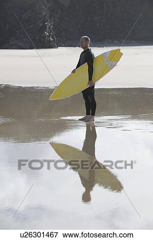Man carrying surfboard on beach side view View Large Photo Image Stock Photo - Man carrying surfboard on beach side view. Fotosearch