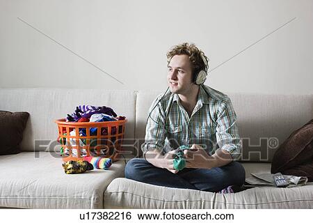 Man folding socks wearing headphones sitting on sofa View Large Photo Image Stock Photograph - Man folding socks wearing headphones sitting on sofa. Fotosearch
