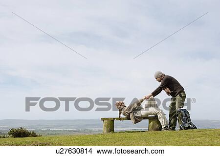 Picture - Man Helping Girlfriend up from a Park Bench. Fotosearch