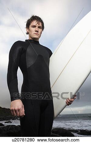 Man holding surfboard on beach portrait View Large Photo Image Stock Image - Man holding surfboard on beach portrait. Fotosearch