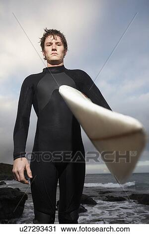 Man holding surfboard on beach portrait View Large Photo Image Stock Image - Man holding surfboard on beach portrait. Fotosearch