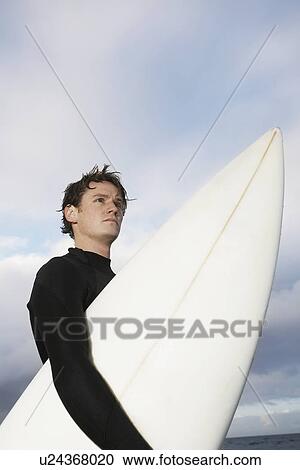Man holding surfboard on beach side view low angle view View Large Photo Image Stock Image - Man holding surfboard on beach side view low angle view. Fotosearch