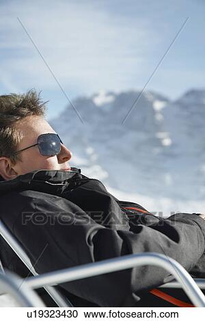 Man in winter coat and sunglasses sitting in arm chair by mountains View Large Photo Image Stock Image - Man in winter coat and sunglasses sitting in arm chair by mountains. Fotosearch