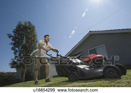 Stock Photo - Man moving lawn low angle. Fotosearch