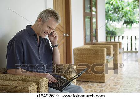 Man on Patio Using Cell Phone and Laptop View Large Photo Image Stock Photo - Man on Patio Using Cell Phone and Laptop. Fotosearch